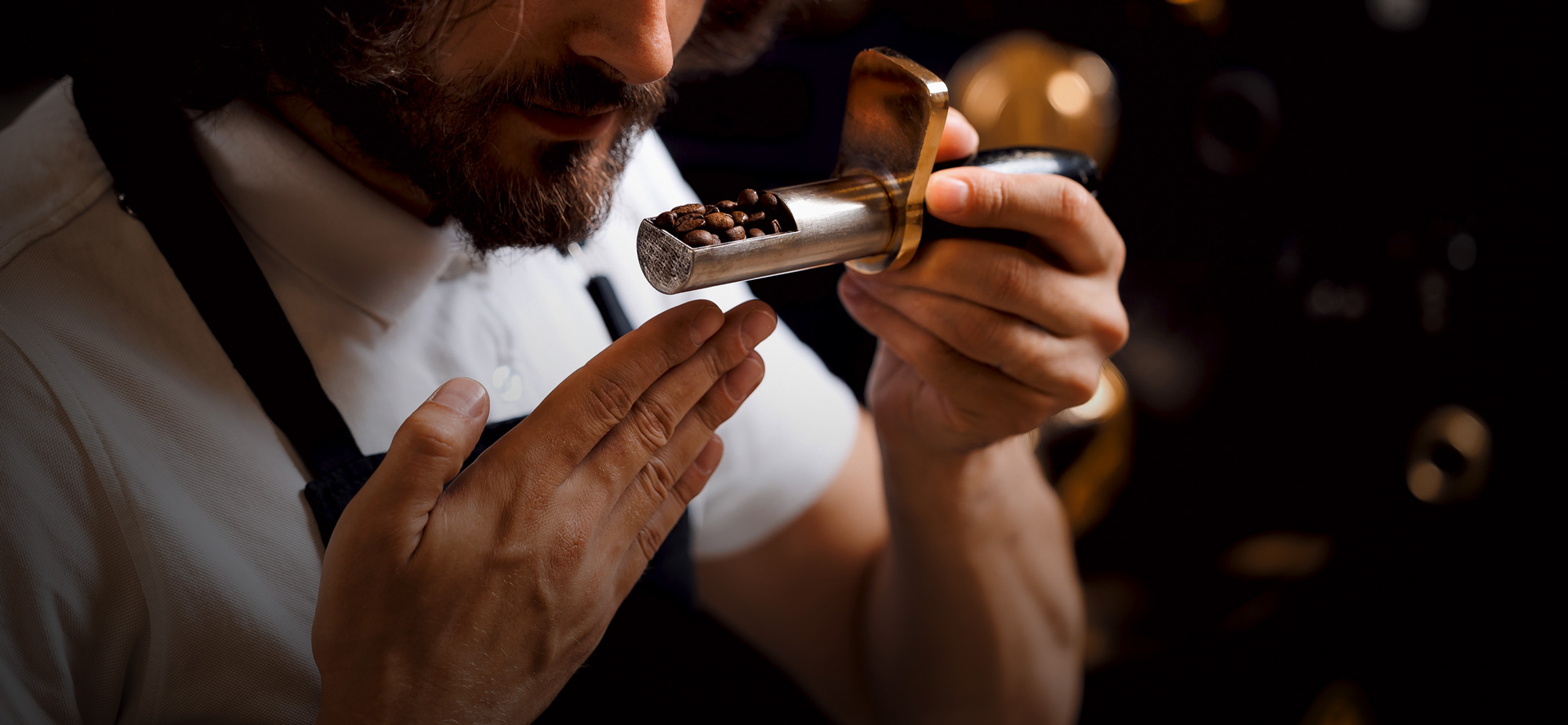 Valutazione sensoriale dei chicchi di caffè Primo piano di un uomo che odora dei chicchi di caffè