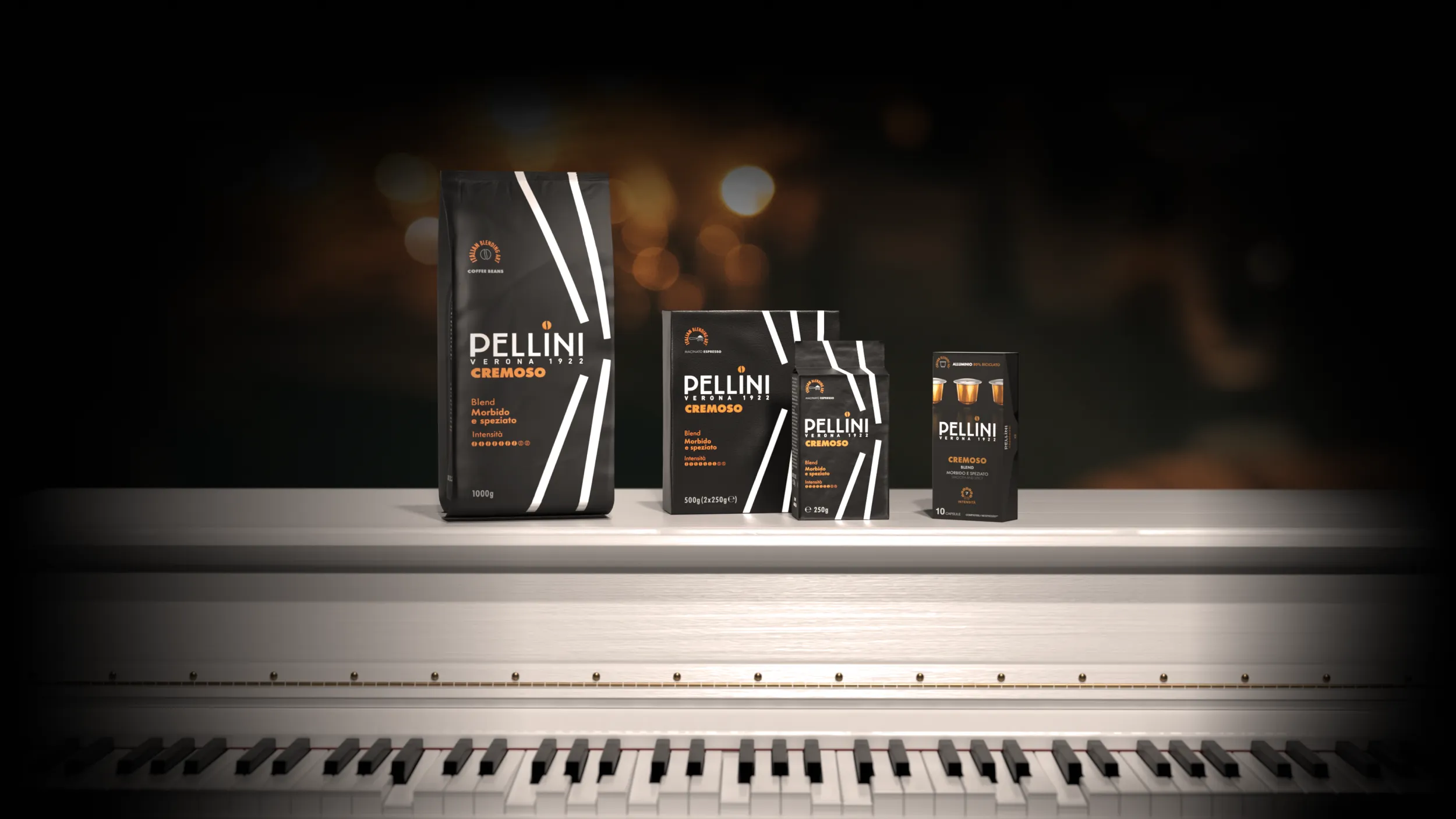 Confezioni di caffè Pellini miscela Cremoso nei formati in grani, macinato espresso e capsule, disposti su un pianoforte