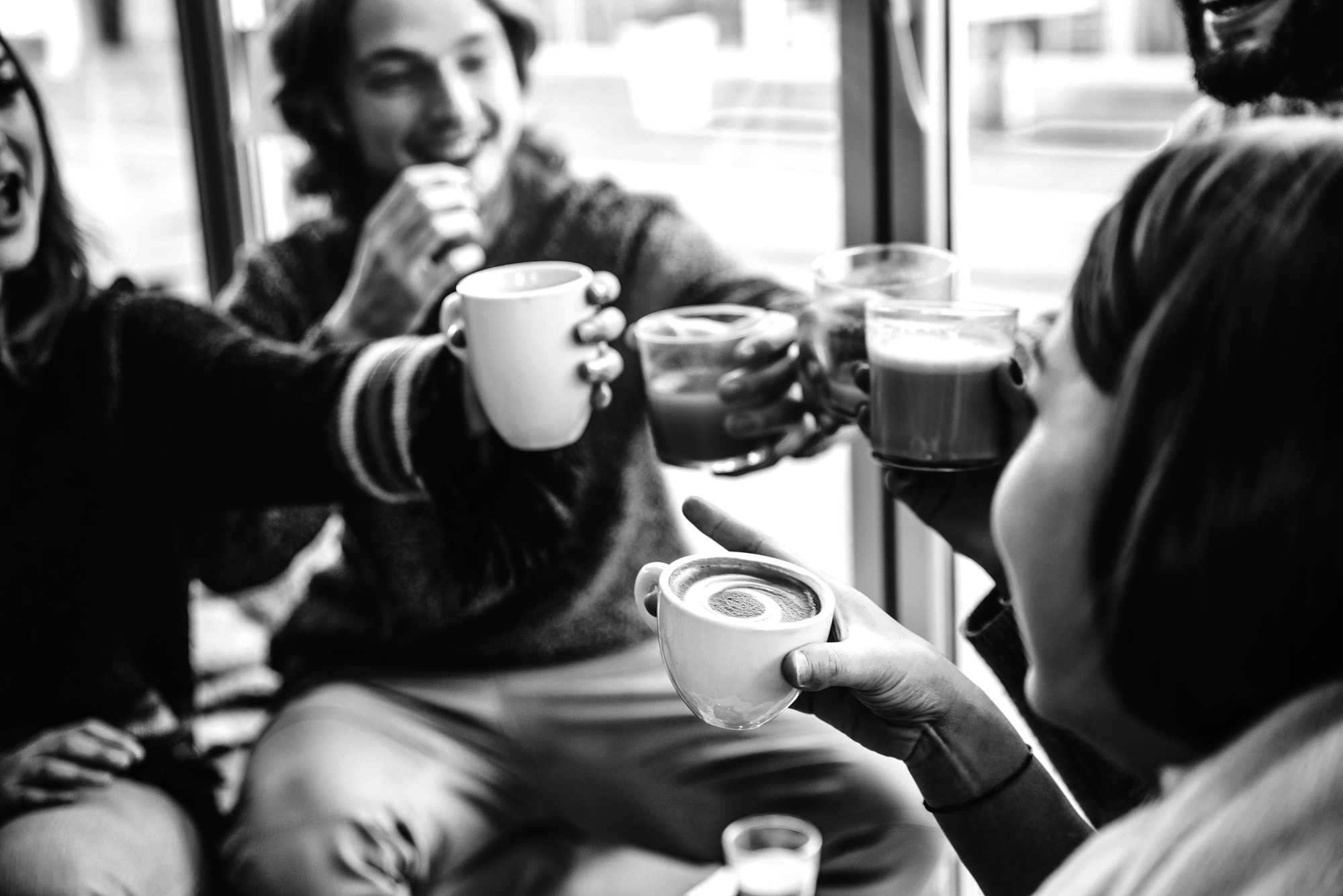 Gruppo di ragazzi sorridenti che bevono caffè al bar