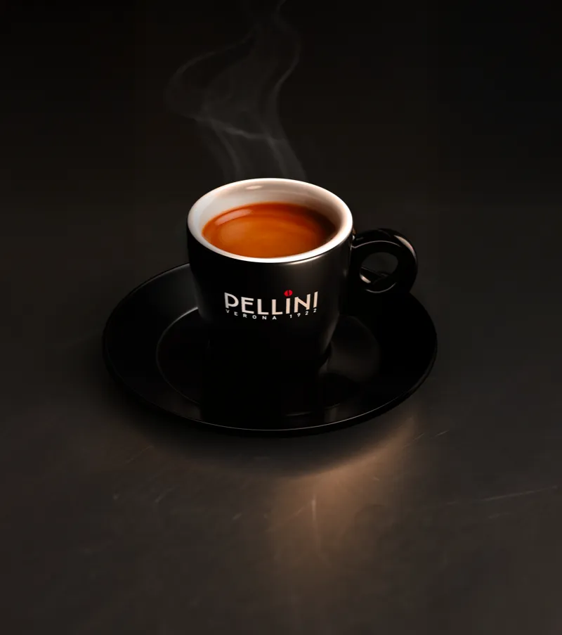 Tazzina di caffè nera brandizzata Pellini su tavolo nero